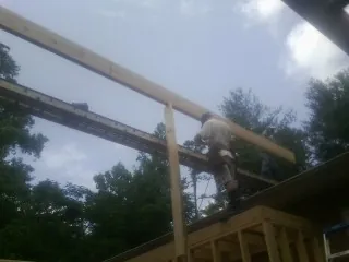 Carpenter setting a ridge beam over a new addition frame — Ice Dam Removal by Roofing Brothers in Omega