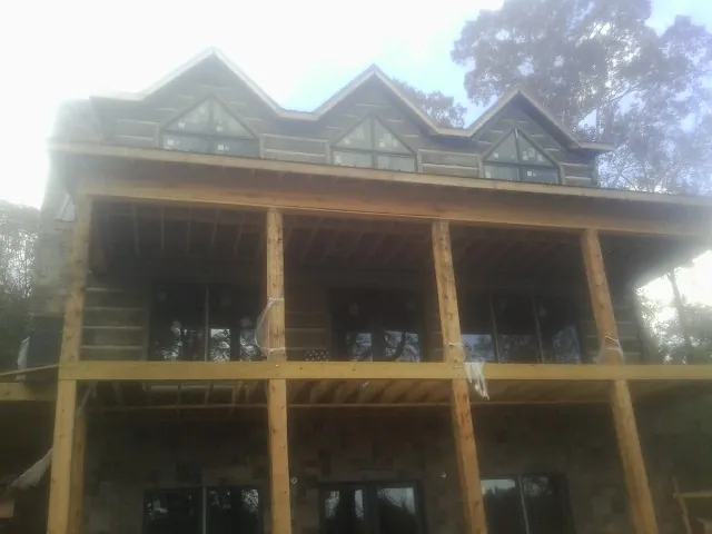 Dormers and porch framing on a large log home under construction — Roof Coating work by our crew in Omega