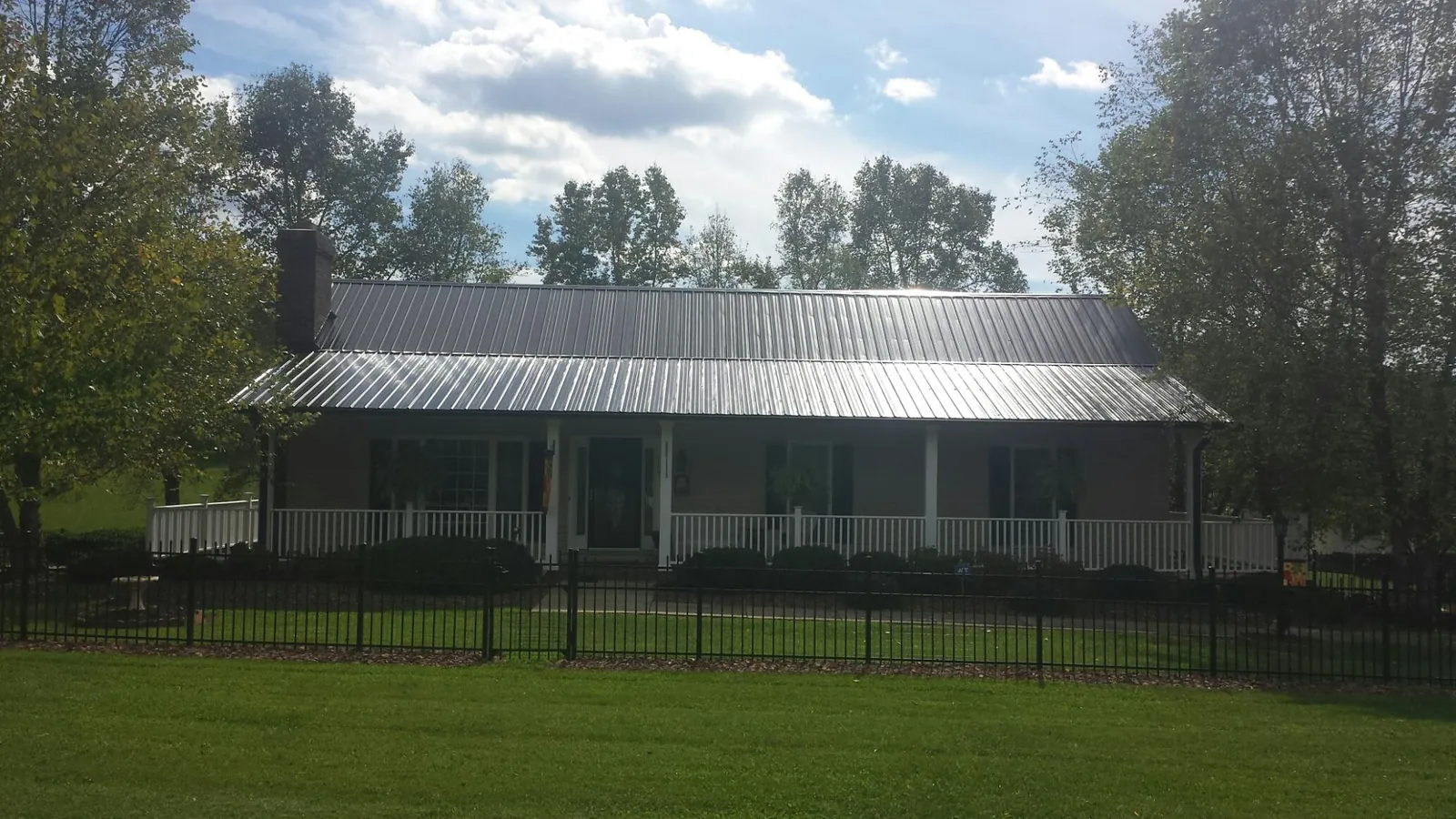 Gray metal roof on a brick ranch with a full width front porch — Gutter Guard Installation work by our crew in Omega