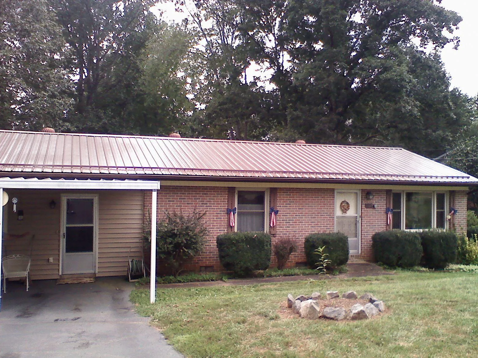 Bronze metal roof and carport on a brick ranch home — Roof Repair work by our crew in Omega