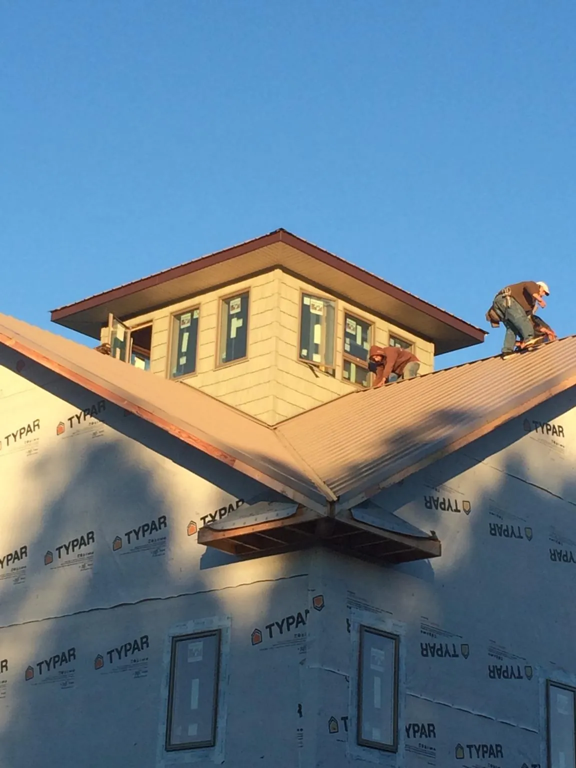 Roofers working around a rooftop cupola on a new metal roof at sunset — Roof Waterproofing in Omega by Roofing Brothers